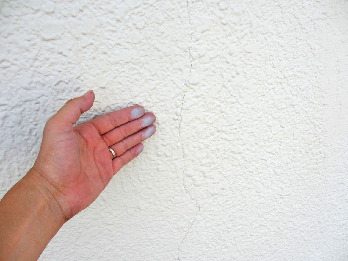 壁のチョーキングを触る手